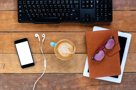 Office desk table with smart phone, headphone,keyboard,notebook,tablet and cup coffee.Top view with copy space.Business analysis and strategy concept.の写真素材