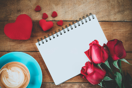 Red roses, leather notebook, pen,heart and cup of coffee on wooden background with copy space.Valentines Day background concept, Wedding day.Top view vintage toneの写真素材