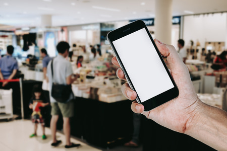Man hands holding smart phone with blank screen in supermarket, light bokeh background.の写真素材