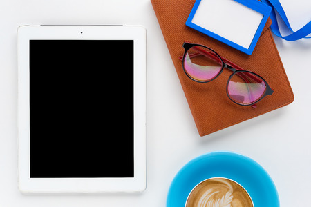 Modern White office desk table with eyeglasses,tablet,notebook,name card and cup of coffee.Top view with copy space.Working desk table concept.の写真素材