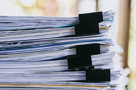 Stack of business report paper file on modern white office desk with bokeh background.