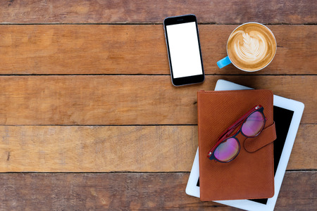 Office desk table with leather notebook,smart phone,tablet,eyeglasses and cup of coffee.Top view with copy space.Working desk table concept.の写真素材