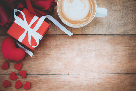 Red roses,heart,gift box and cup of coffee on wooden background with copy space.Valentines Day background concept, Wedding day.Top view vintage toneの写真素材