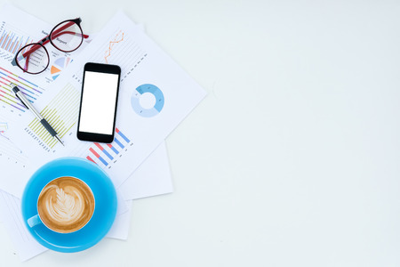Modern white Office desk table with  blank screen smart phone,pen,analysis chart and cup of coffee .Top view with copy space.Business analysis and strategy concept.の写真素材