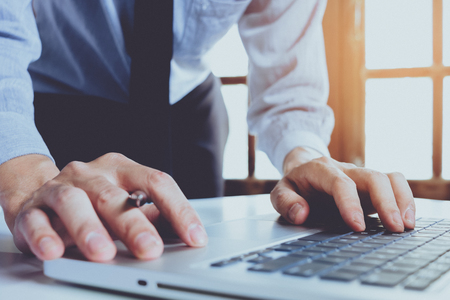 Businessman hand working on laptop computer on modern white desk as concept business workingの写真素材