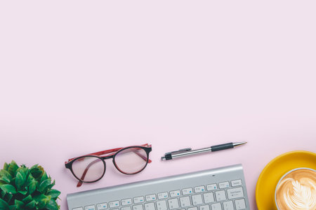 Office desk with computer, eye glass, Pen, Cup of coffee on pink background, Top view with copy space, Mock up.の写真素材