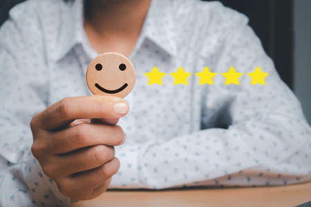 Business woman hand holding smiley face emoticon on virtual touch screen.good feedback rating and positive customer review, experience, satisfaction survey, world mental health day conceptの写真素材