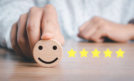 Business woman hand holding smiley face emoticon on virtual touch screen.good feedback rating and positive customer review, experience, satisfaction survey, world mental health day conceptの写真素材