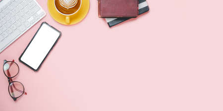 Pink office desk table with blank screen smart phone, calculator, notebook, eyeglass and cup of coffee .Top view with copy space.Office desk table concept.の写真素材