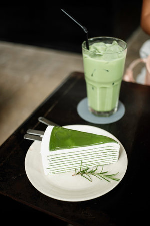 Japanese green tea cake and matcha green tea milk frappe on wooden desk at cafe.の写真素材
