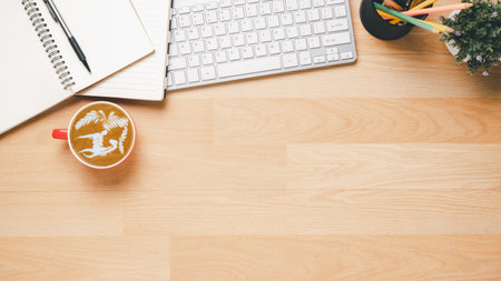 Flat lay, Wooden office desk with notebook, keyboard computer, pen and coffee, Top view with copy space, Mock up.の写真素材