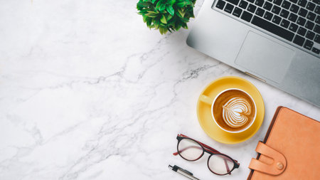 White office desk with laptop computer, notebook, pen, eyeglass with cup of coffee, top view with copy space, Mock up.の写真素材