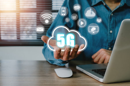 Global communication network concept, Person hand holding 5G icon on virtual screen on office desk...
