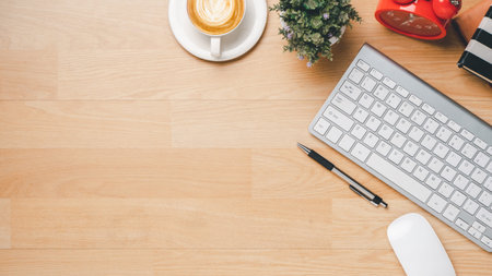 Office wooden desk with keyboard, notebook, pen, mouse and cup of coffee, Top view wth copy space,...