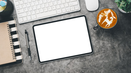 Office workplace with blank screen tablet, notebook, keyboard, mouse, pen and cup of coffee, Top view flat lay.の写真素材