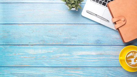 Wooden desk workplace with laptop computer, notebook, pen and cup of coffee, Top view flat lay with copy space.の写真素材