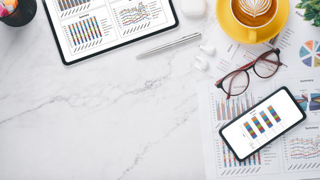 Tablet and smart phone screen display with charts and reports on office desk workplace. Top view flat lay with copy space.の写真素材
