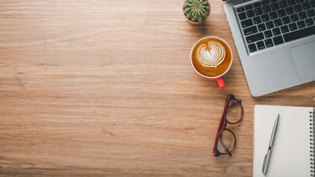 Wooden desk workplace with laptop computer, notebook. eyeglass, pen and cup of cofeee, Top view flat lay with copy space.の写真素材