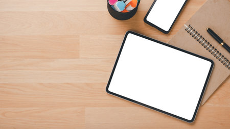 Office wooden desk workplace with blank screen tablet and smart phone, notebook and pen, Top view flat lay with copy space.の写真素材