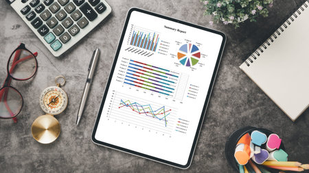 Tablet with charts and reports on office desk workplace. Top view flat lay