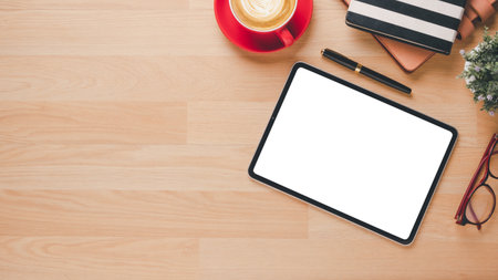 Office wooden desk with blank screen tablet, notebook, pen, eyeglass and cup of coffee, Top view flat lay with copy space.の写真素材