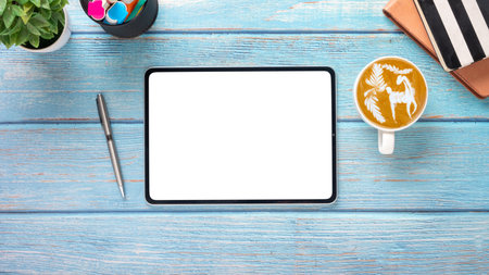 Wooden desk workplace with blank screen tablet, notebook, pen and cup of coffee, Top view flat lay with copy space.の写真素材