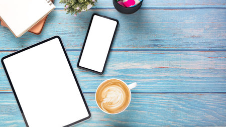 Office desk workplace with blank screen tablet and smartphone, notebook and cup of coffee, Top view...