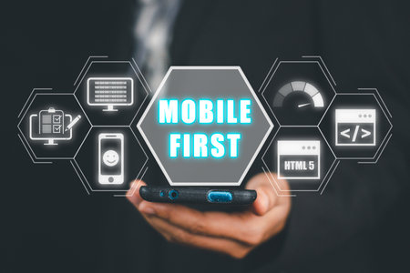 Mobile first concept, Person hand using smart phone with mobile first icon on virtual screen, Digital marketing, office desk.の写真素材