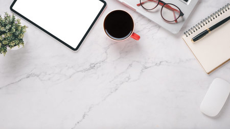 White office desk workplace with blank screen tablet, laptop, mouse, notebook, pen and cup of...