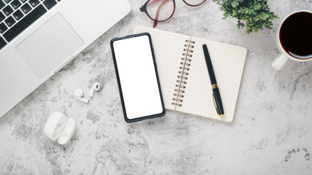 White office desk workplace with blank screen smart phone, laptop, eyeglass, notebook, pen and cup of coffee, Top view flat lay with copy space.の写真素材