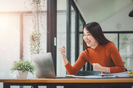 Businesswoman happy and cheerful for successful on project via laptop in office space.の写真素材