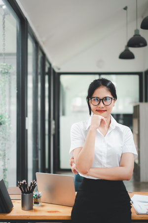 Successful businesswoman standing in creative office and looking at camera. Woman entrepreneur in a coworking space smiling.の写真素材