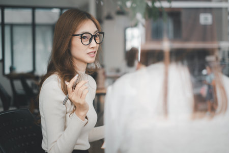 Two young businesspeople using business data while sitting in a boardroom. Two business colleagues having a discussion during a meeting.の写真素材