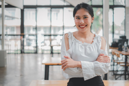 Successful businesswoman standing in creative office and looking at camera. Woman entrepreneur in a coworking space smiling.の写真素材