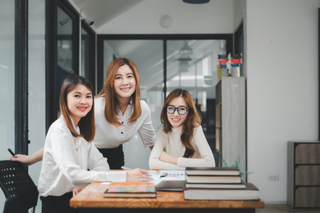 Portrait of a smiling group of diverse corporate colleagues analyzing documents while sitting on a table in office.の写真素材