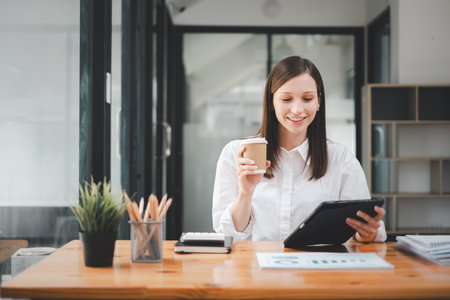 Business woman using tablet and business paper for doing math finance on office desk, tax, report, accounting, statistics, and analytical research conceptの写真素材