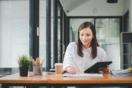 Business woman using tablet and business paper for doing math finance on office desk, tax, report, accounting, statistics, and analytical research conceptの写真素材
