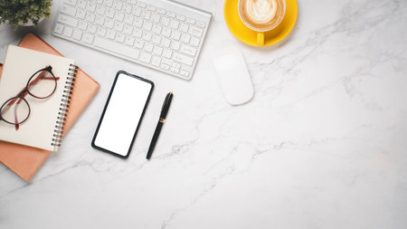 Office desk workplace with blank screen smarphone, pen, eyegalss, keyboard, notebook and cup of coffee, Top view flat lay with copy space.の写真素材