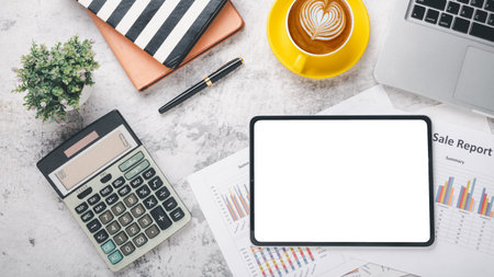Overhead view of a well-organized desk featuring a digital tablet with a blank screen, financial reports, a calculator, and a cup of coffee, symbolizing strategic business planning and analysis.の写真素材