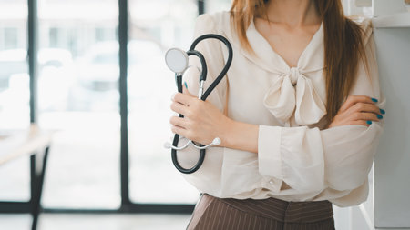 A confident healthcare professional stands poised in her clinic, stethoscope in hand, projecting a blend of competence and approachability essential in medical practice.の写真素材