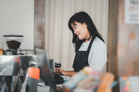 Beautiful woman barista preparing cup of coffee for customer in coffee shop.の写真素材