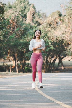 A joyful runner wearing pink leggings and white sneakers exudes happiness and health while jogging...