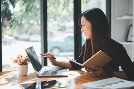 Smiling beautiful businesswoman using laptop sitting at desk in office.の写真素材
