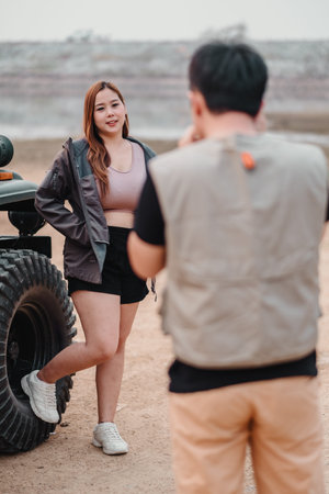 Young woman stands relaxed, posing by an off-road car, in a casual conversation with an unseen companion.の写真素材
