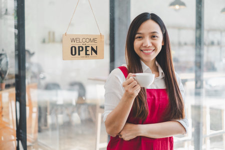Coffee business concept, Beautiful woman smiles at camera offering hot coffee at coffee shop.