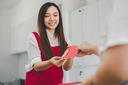 A woman with a beaming smile receives a red envelope, a gesture steeped in cultural significance, conveying blessings and good fortune.の写真素材