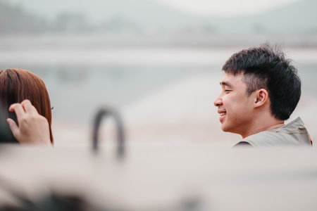 Profile of a smiling young man in a casual conversation with a focus on his joyful expression, in an outdoor setting with soft focus background.の写真素材