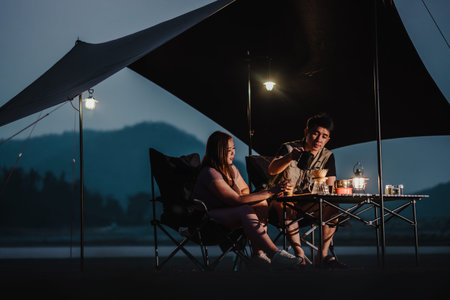 As night falls, a couple savors their coffee and enjoys intimate conversation at their well-lit...