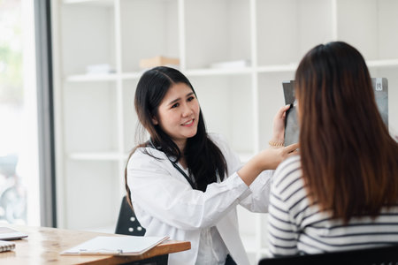Female doctor consulting with patient, discussing medical results in a modern clinic office, providing professional healthcare advice.の写真素材