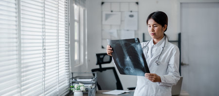 Female doctor in white coat carefully examining an X-ray image in a well-lit, modern medical office.